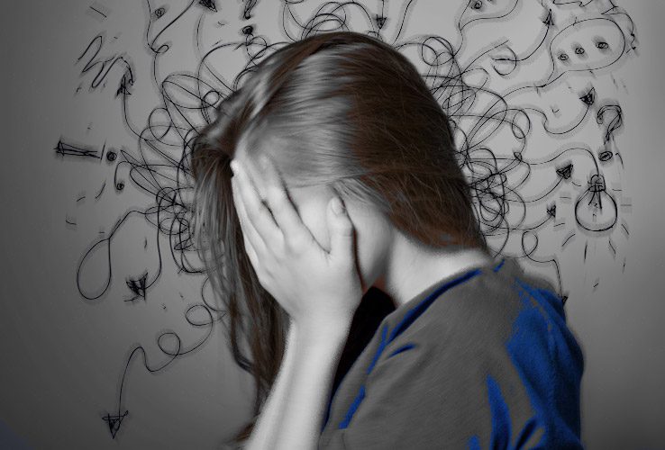 Image of an anxious young woman with her head in her hands.