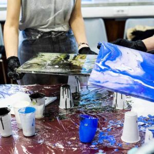 Two adults learning acrylic pour painting as part of a group art therapy session.