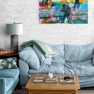 A thought-provoking abstract painting titled "Bullets Travel Distance & Time" by Adrian Reynolds hangs on a brightly coloured wall in a modern studio apartment.